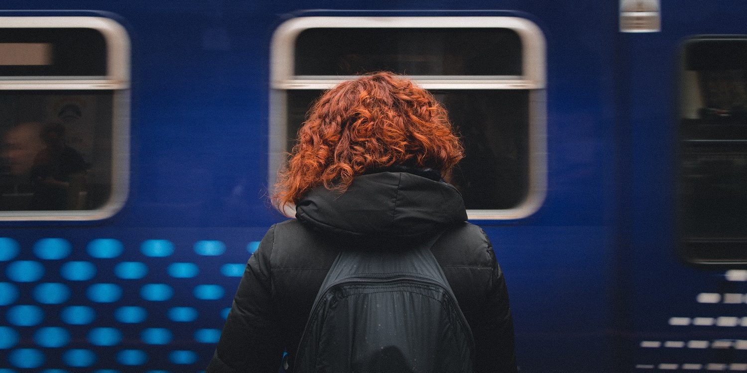 femeie, tren, asteptare O femeie asteapta in gara, in timp ce un tren trece prin fata ei.