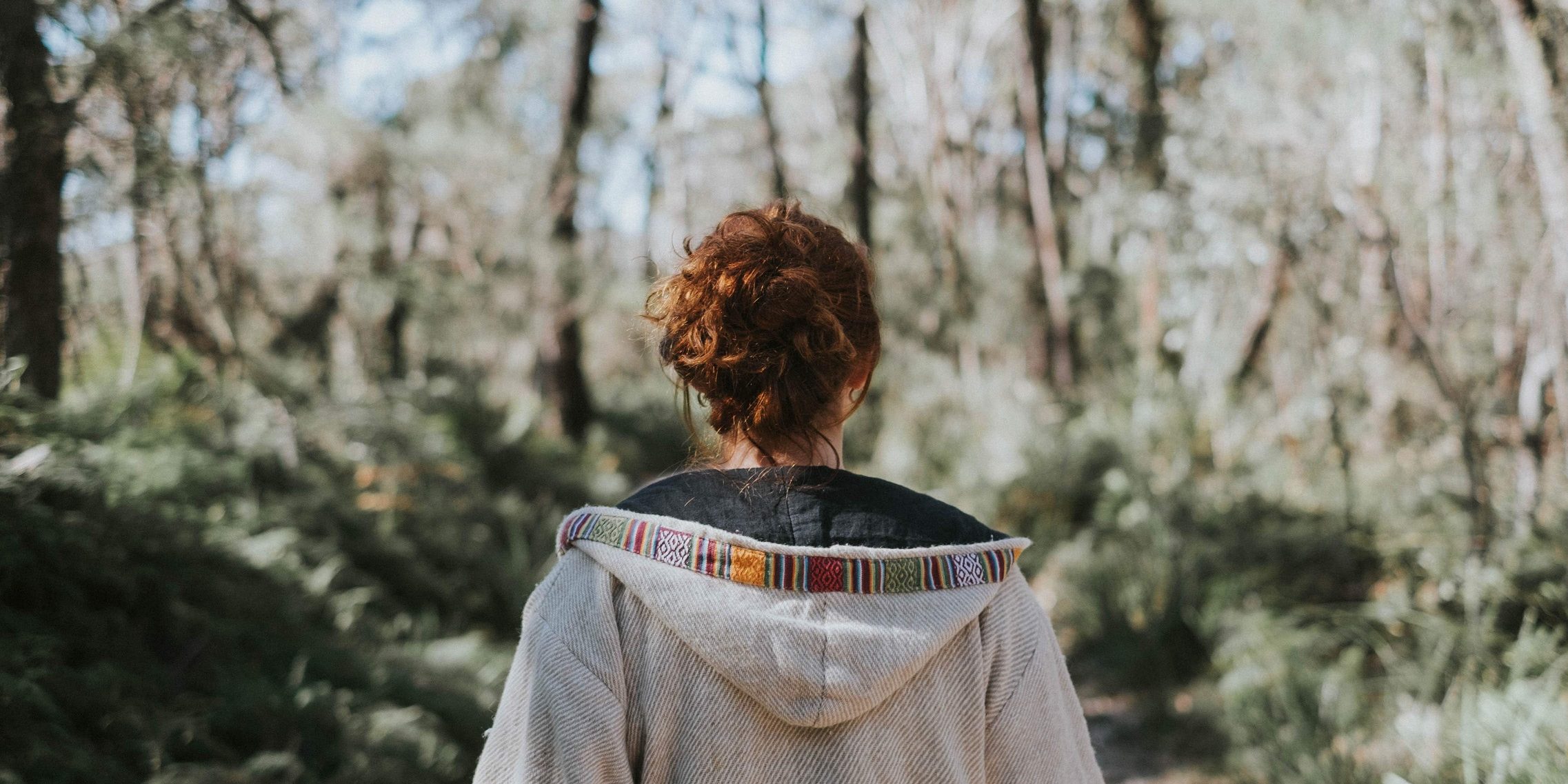 O femeie sta cu spatele in padure