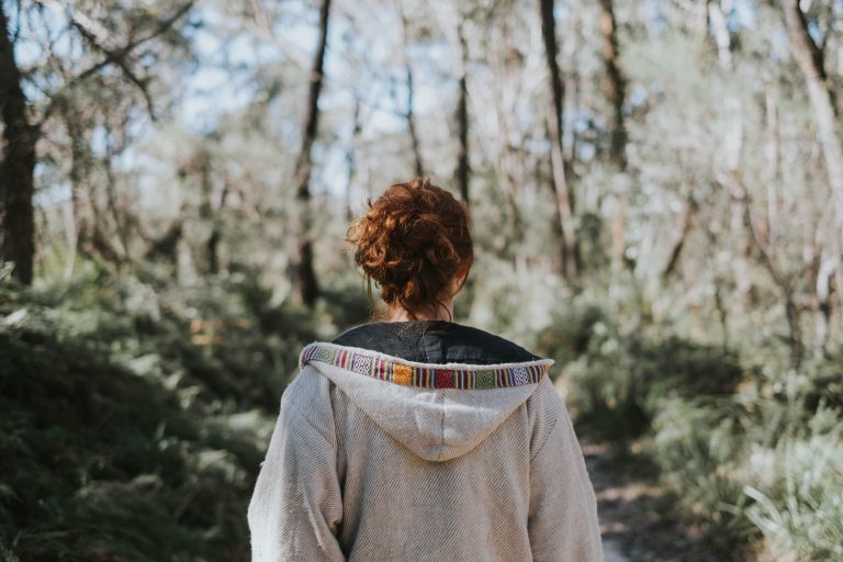 O femeie sta cu spatele in padure