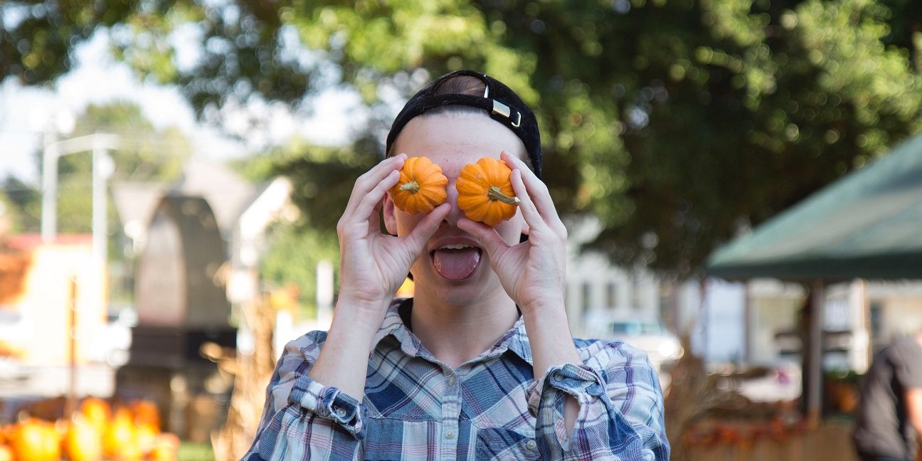 O fata tine doi dovleci mici in dreptul ochilor